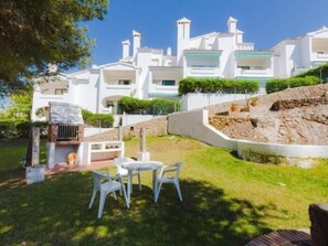 Stunning multi-story residence with a well-maintained lawn and patio area featuring a grill and two chairs.