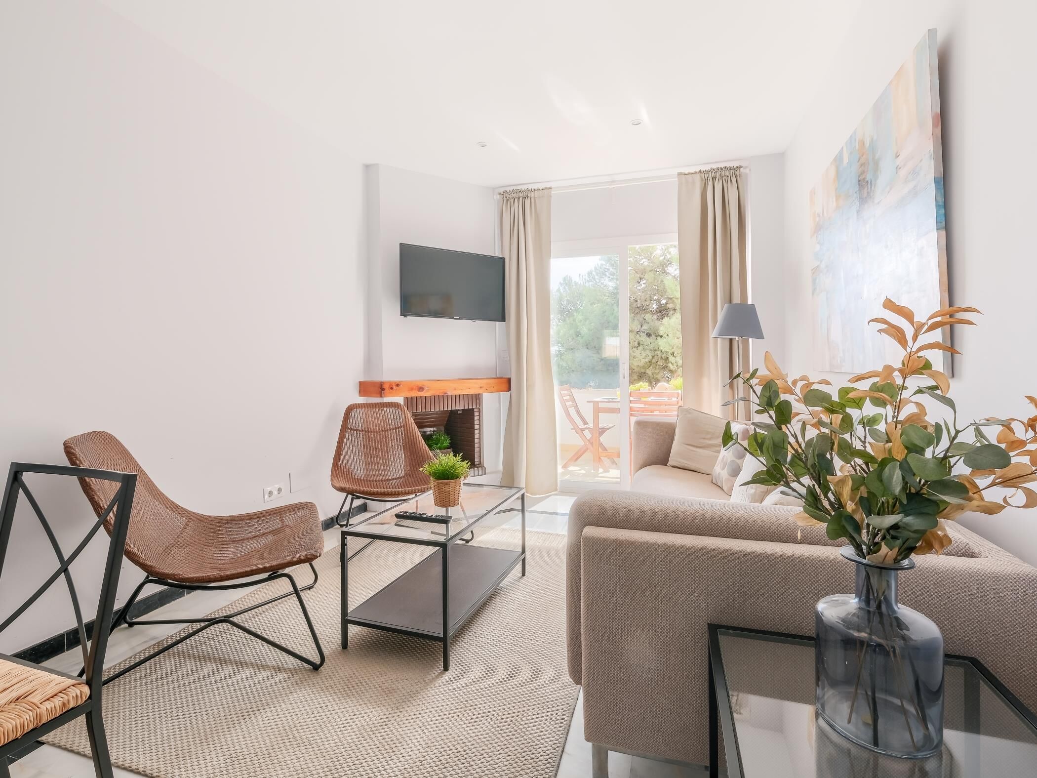 Uma sala de estar moderna com um sofá, duas poltronas, uma mesa de centro e uma lareira.
