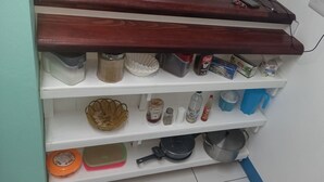 A kitchen shelf with various kitchen items including containers, a basket, and cookware. - Cozy vacation retreat (Roseau)