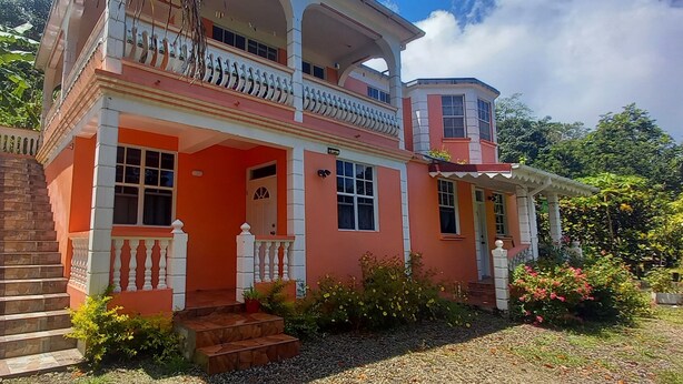 A two-story house with a balcony, a porch, and a small garden area. - Cozy vacation retreat (Roseau)