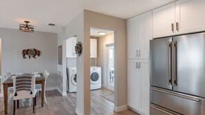 A modern kitchen with a stainless steel refrigerator, white cabinets, and a dining area with a table and chairs.