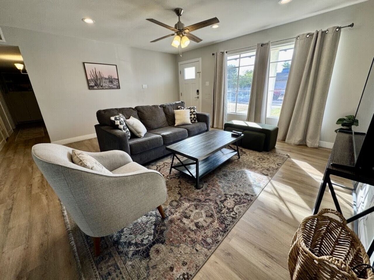 A living room with a sofa, armchair, coffee table, and a ceiling fan.