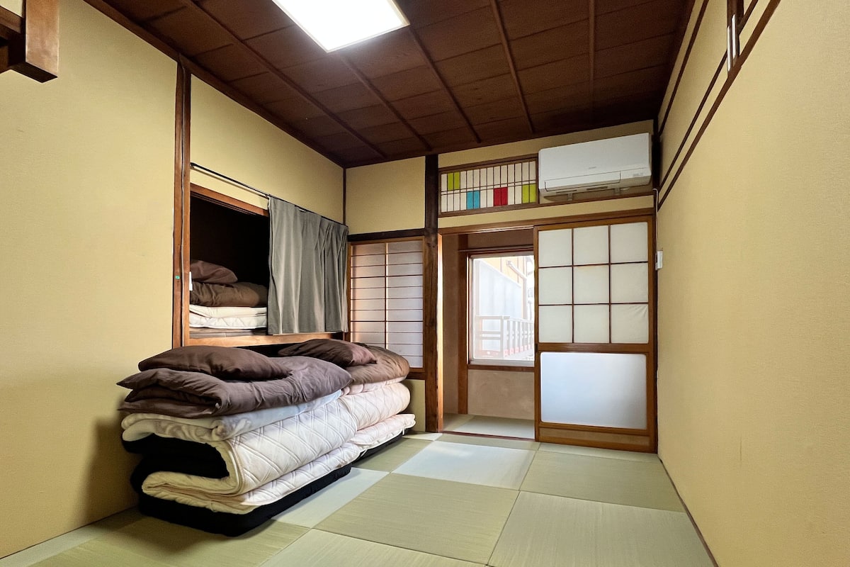 Ett traditionellt japanskt rum med tatamimattor på golvet, en futonmadrass, skjutbara shojidörrar och en takfläkt.