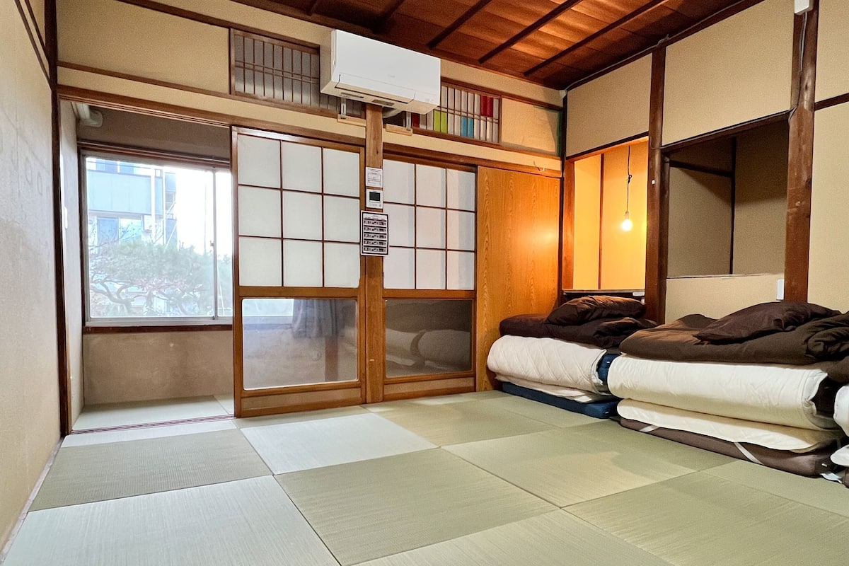 Ett traditionellt japanskt rum med tatamimattor på golvet, en futonmadrass, skjutbara shojidörrar och ett litet fönster.