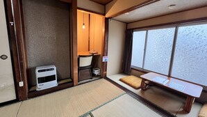 Una habitación japonesa tradicional con suelo de tatami, futón, una mesita y un calentador.