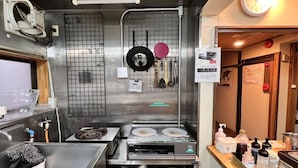 Una cocina con electrodomésticos de acero inoxidable, un reloj y varios utensilios colgados en la pared.