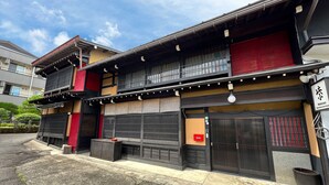 Un edificio japonés tradicional con fachada roja y negra, un vestíbulo cubierto y un cartel que indica que es una residencia para trabajadores.