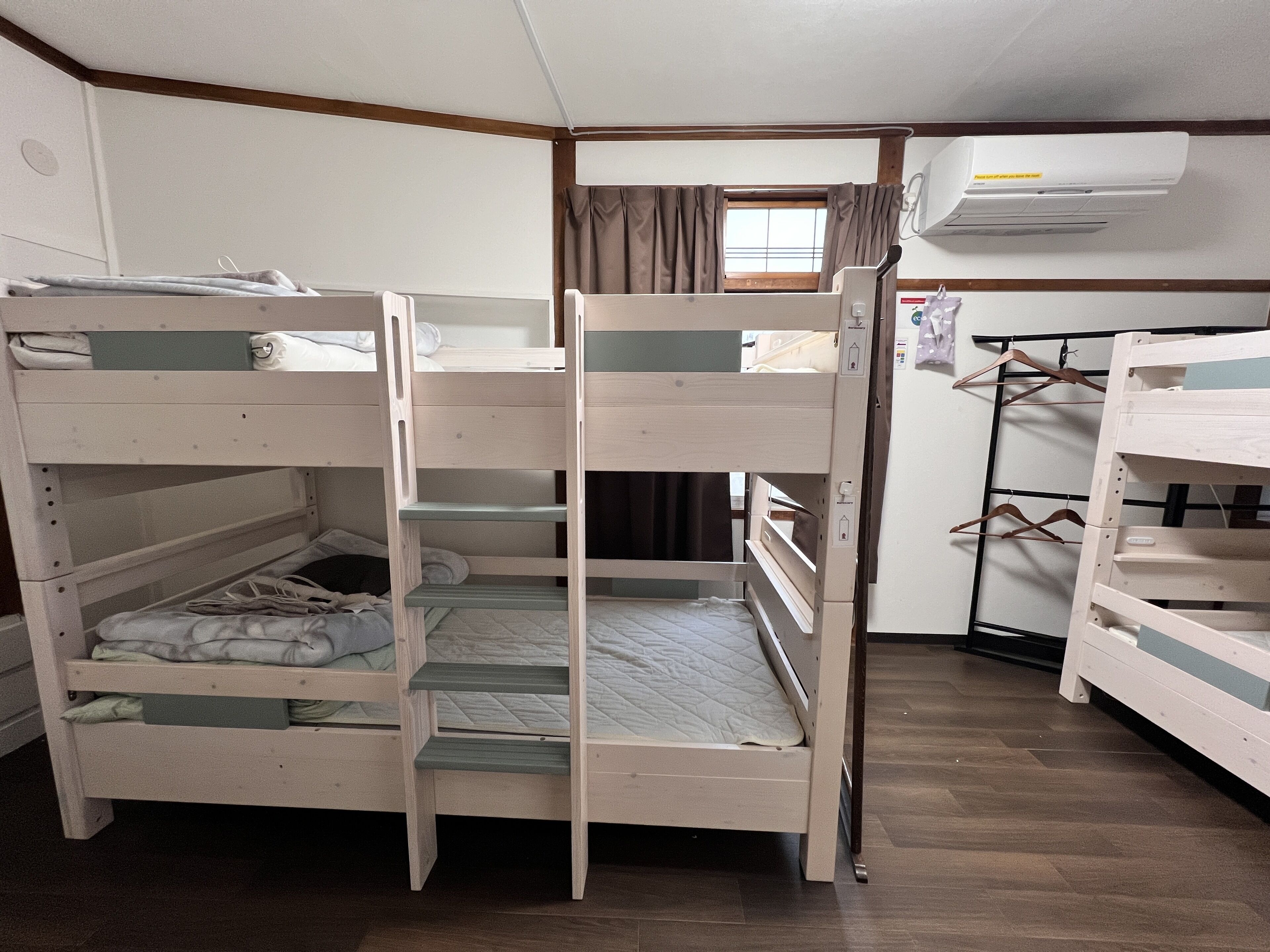 Une chambre avec des lits superposés, une armoire et un appareil de climatisation.