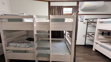 Une chambre avec des lits superposés, une armoire et un appareil de climatisation.
