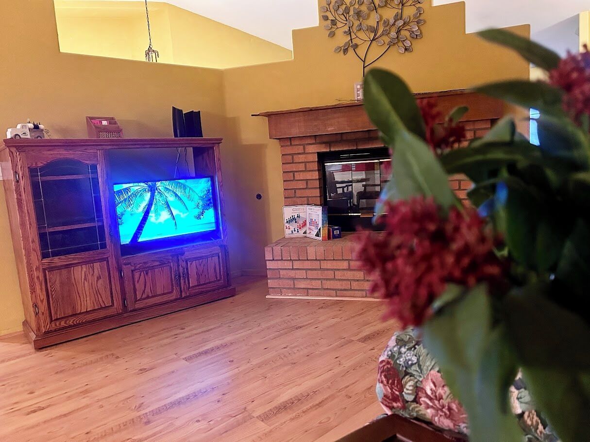 A living room with a wooden entertainment center, a fireplace, and a television.