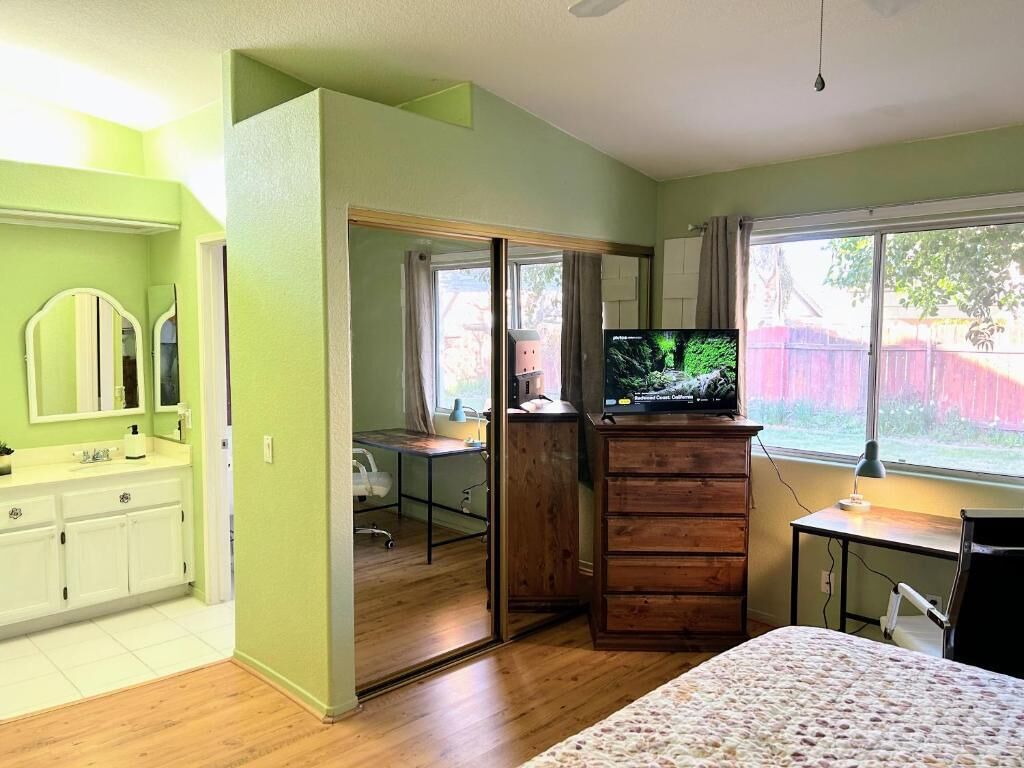 A bedroom with a bed, a TV, a desk, and a wardrobe.