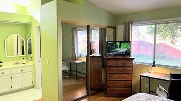A bedroom with a bed, a TV, a desk, and a wardrobe.