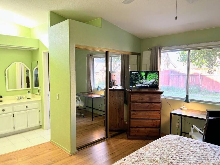 A bedroom with a bed, a TV, a desk, and a wardrobe.