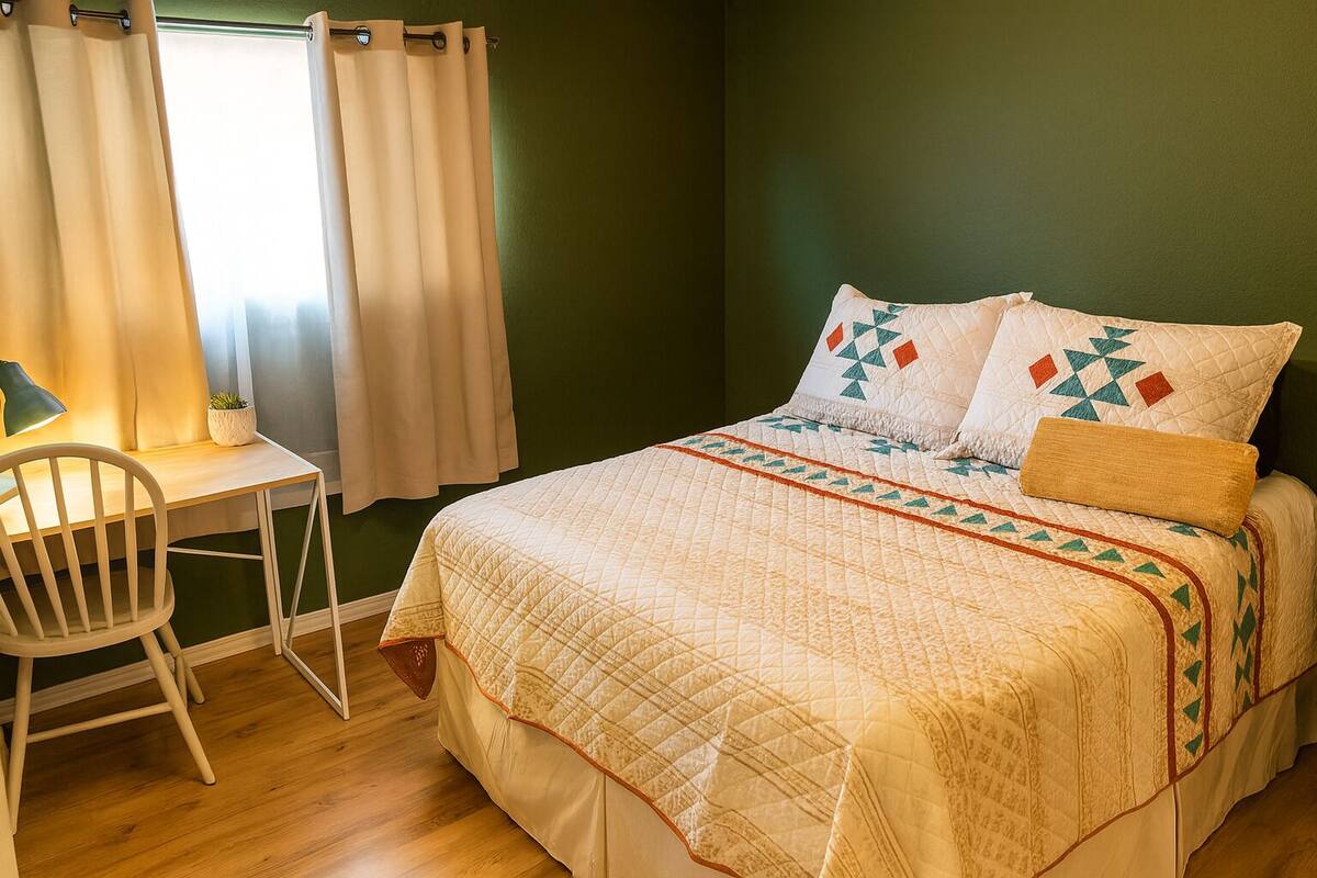 A bedroom with a bed, a desk, and a chair.