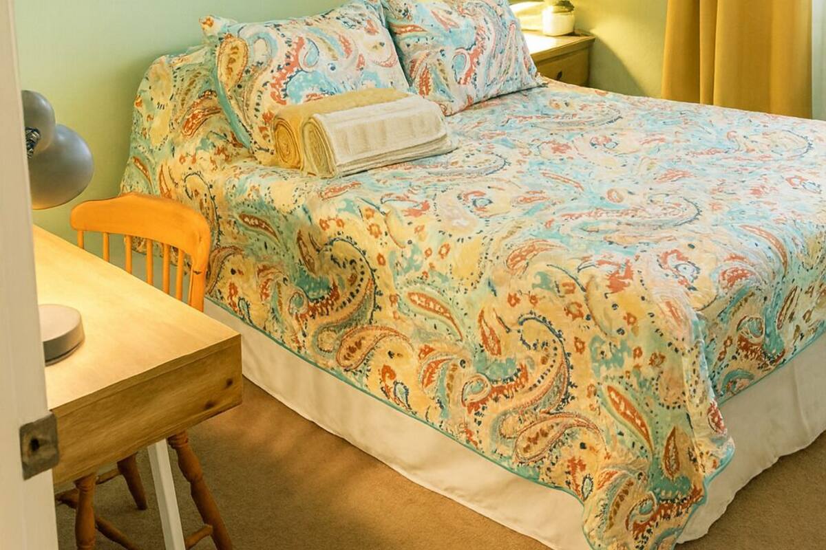 A bedroom with a bed, a desk, and a chair.