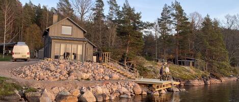 A lakeside cabin with a dock, surrounded by rocks and trees.