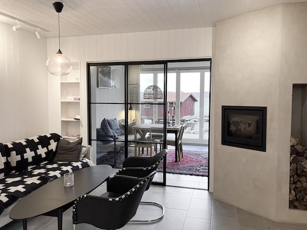 Un intérieur moderne comprenant un coin repas, un canapé et une vue sur une structure en bois au bord de l’eau.