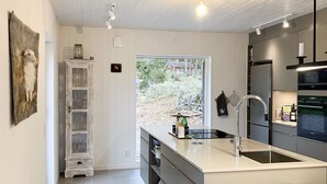 A modern kitchen with a large island, stainless steel appliances, and a view of the outdoors. - Fantastic location next to Lake Sommen (Ydre)