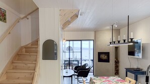 A modern interior with a wooden staircase, a dining area with a floral tablecloth, and a view through large windows. - Fantastic location next to Lake Sommen (Ydre)