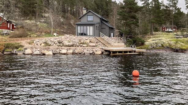 A cabin with a dock extending into a lake, surrounded by trees and a rocky shoreline. - Fantastic location next to Lake Sommen (Ydre)