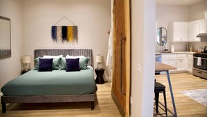 Een slaapkamer met een bed, nachtkastjes en een hangend abstract kunstwerk.