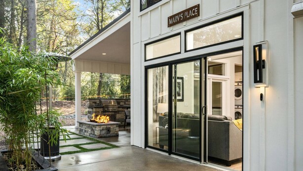 Een modern huis met een overdekte patio, een stenen openhaard en een bord met de tekst 'Marv's Place'.