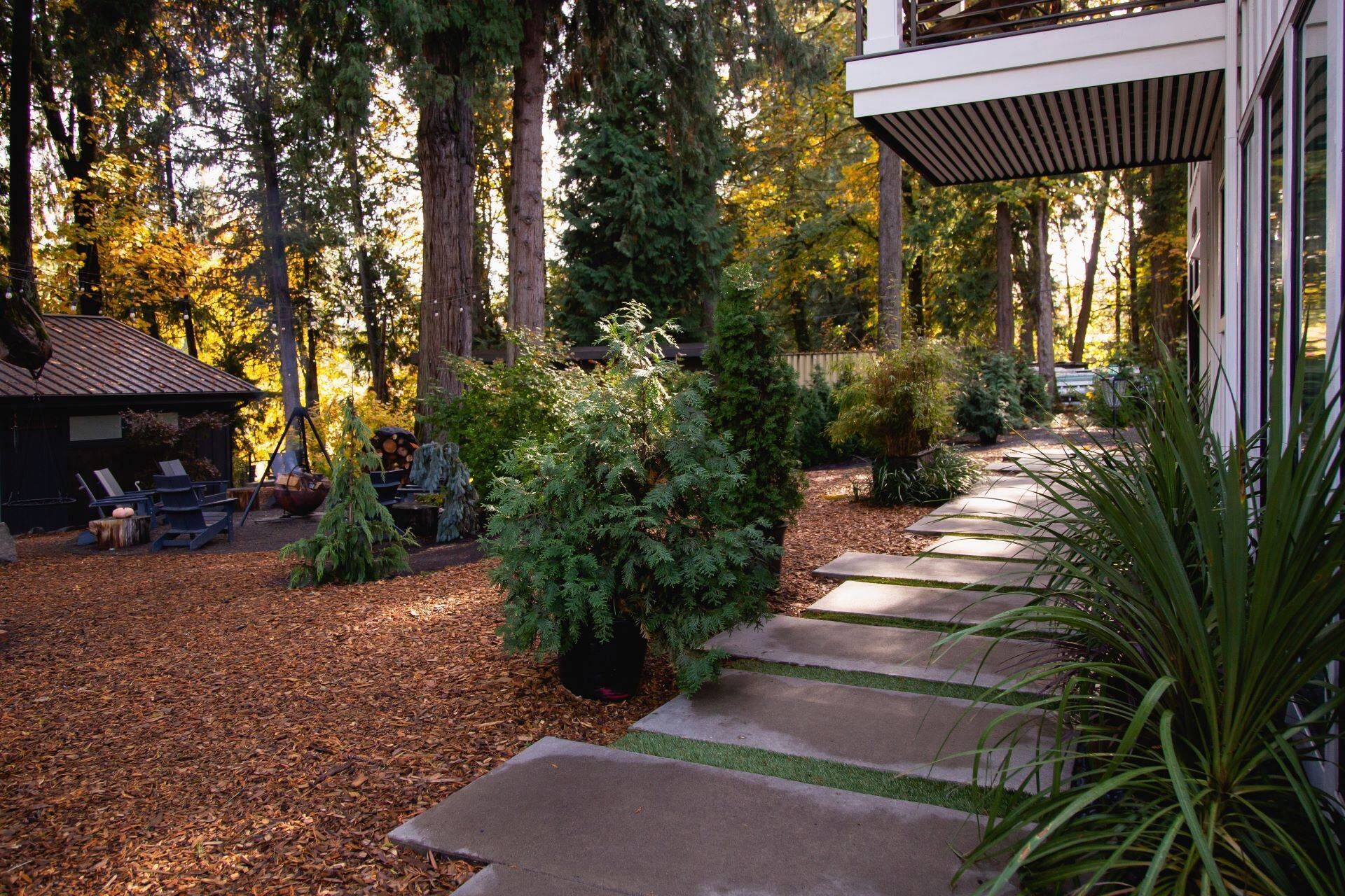 A wooden cabin with a deck, surrounded by a forest.