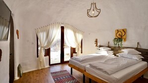 A bedroom with a wooden bed, a large window with curtains, a hanging light fixture, and a wall-mounted plant. - Pensiunea Dealul Verde (Sibiu)