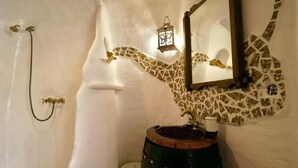 Un baño con una bañera blanca, un lavabo de madera, un espejo y una pared de mosaico.