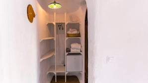 A narrow hallway with white walls and a white shelf unit containing folded towels and a basket. - Pensiunea Dealul Verde (Sibiu)