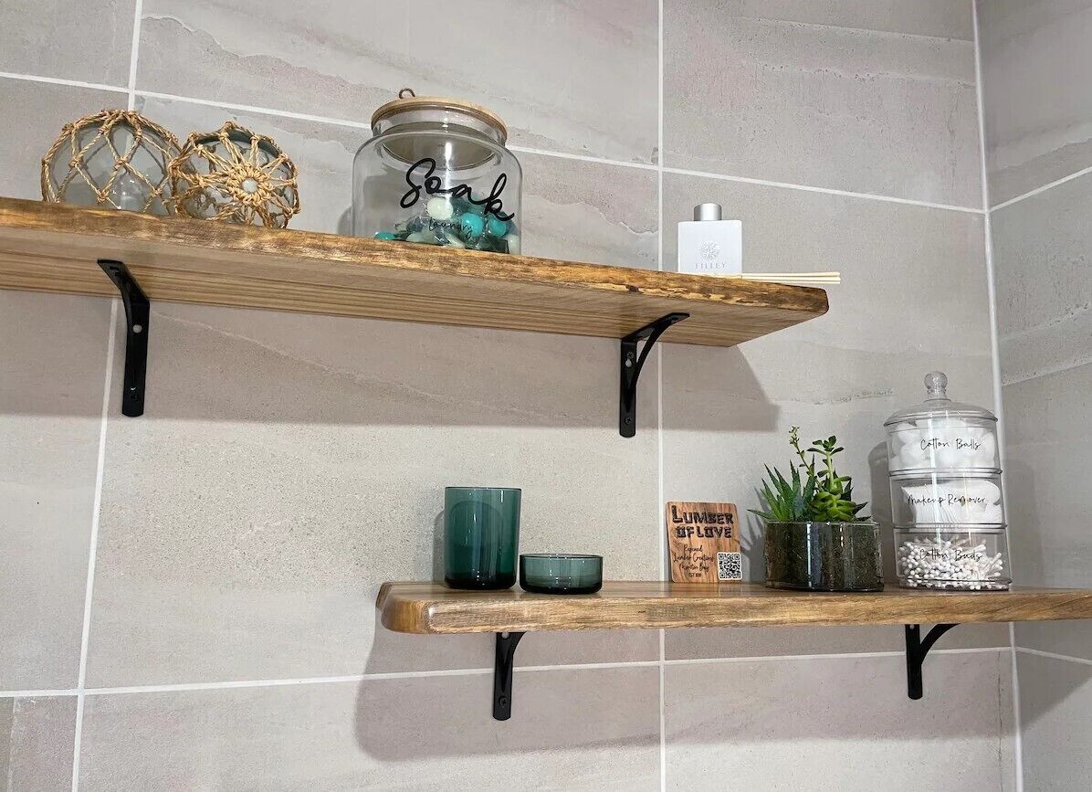 Deux étagères en bois fixées à un mur recouvert de carreaux, chacune contenant divers objets décoratifs et récipients.