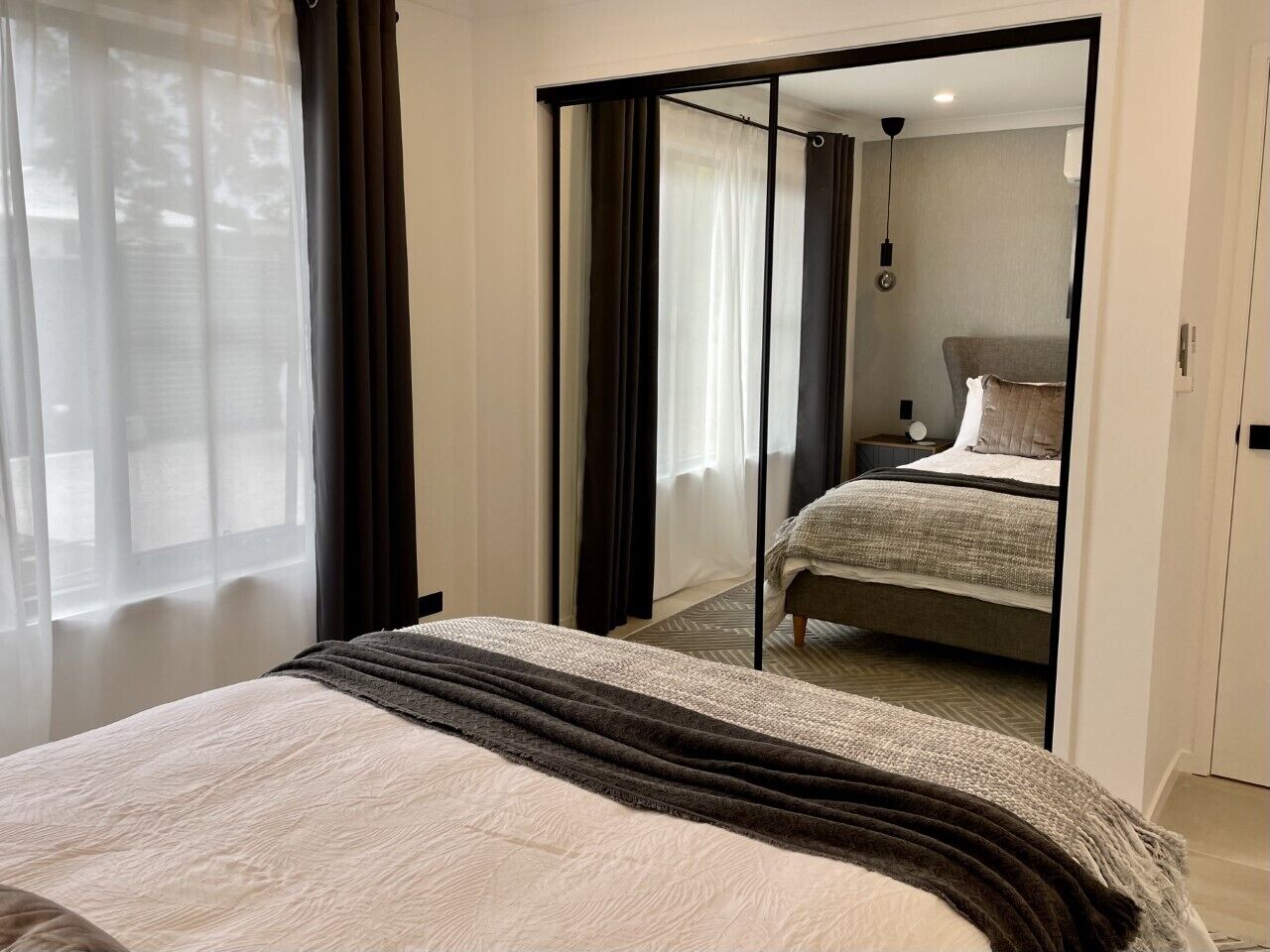 Une chambre avec un lit, une porte coulissante donnant sur une salle de bain et une vue sur le paysage urbain par la fenêtre.