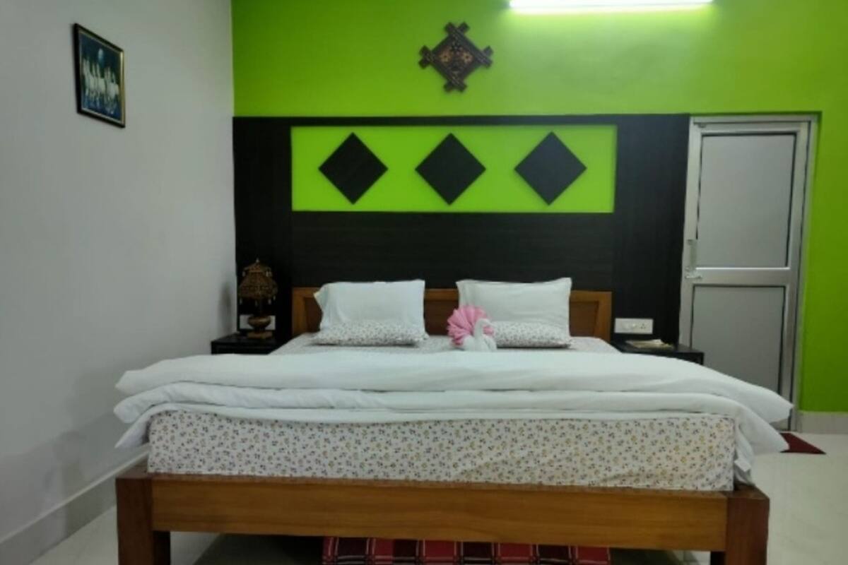 A bed with a floral bedspread, a wooden headboard, and a decorative wall panel above it.