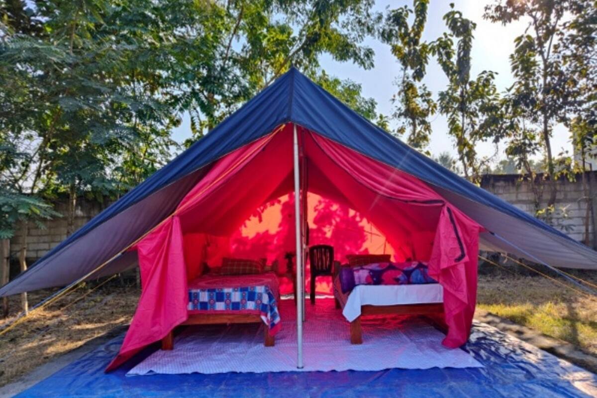 A tent with a bed and a table inside, surrounded by a blue mat.