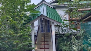 A small shrine-like structure with a green roof, surrounded by dense foliage. - Homocation Changghar Resort (Kaliabar)