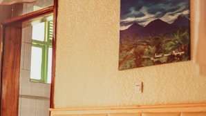 A bed with two pillows and a headboard, a painting on the wall, and a window with a view of greenery. - Nyungwe Hotel by Savany Investments (Kigali)