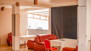 A dining area with a table and chairs, a sofa, and a view through a window. - Nyungwe Hotel by Savany Investments (Kigali)