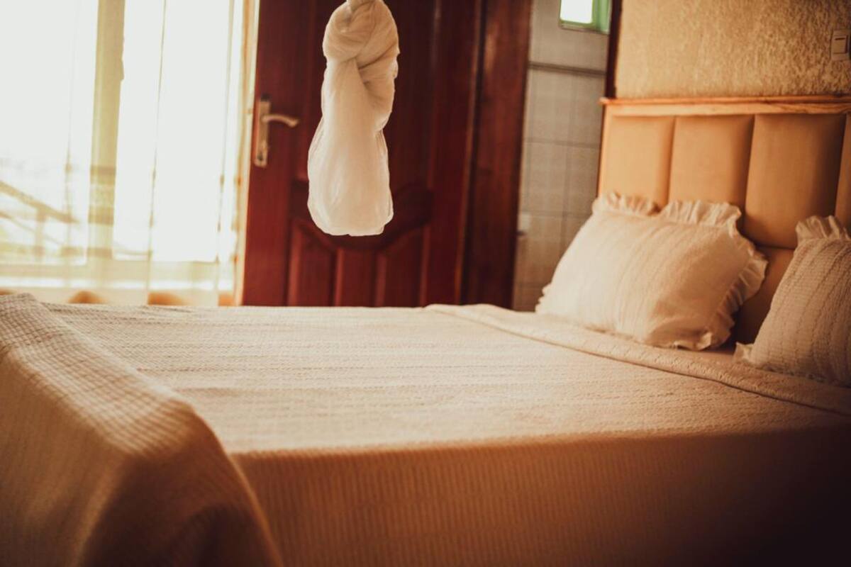 A bed with a wooden headboard, a white blanket, and a hanging towel.