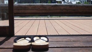 A pair of flip-flops on a wooden deck with a view of buildings in the background. - This is a single building rental of a Kyomachiya that has been in existence since the Meiji Era (1868-1912). The window overlooks the Kamo River and the town of Gion, making it a prime location to enjoy the typical Kyoto scenery. (Kyoto)