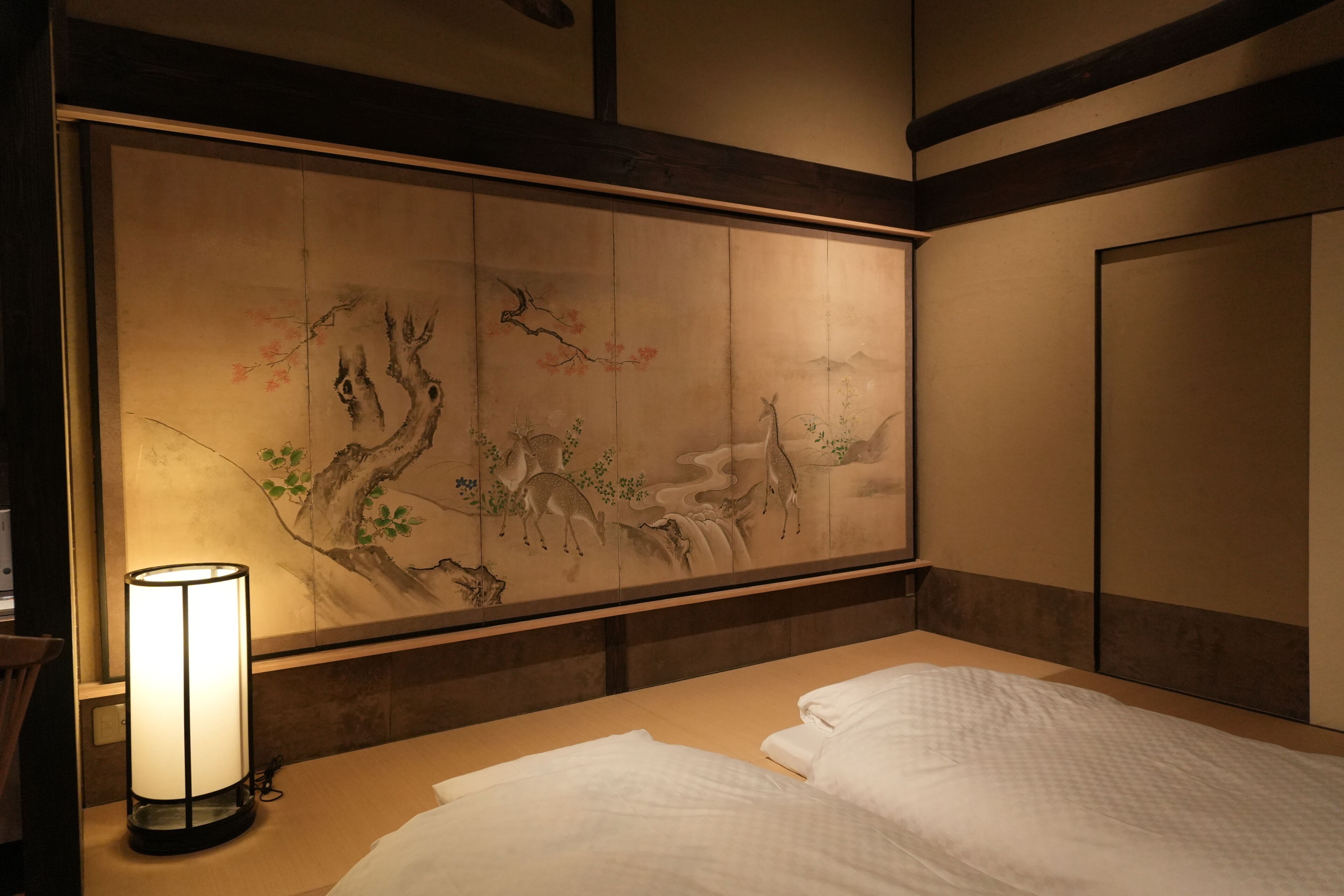 A room with a bed, a wall-mounted artwork, and a bedside table with a lamp.