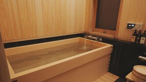 A modern bathroom with a wooden bathtub, a separate shower area, and a toilet. - This is a single building rental of a Kyomachiya that has been in existence since the Meiji Era (1868-1912). The window overlooks the Kamo River and the town of Gion, making it a prime location to enjoy the typical Kyoto scenery. (Kyoto)