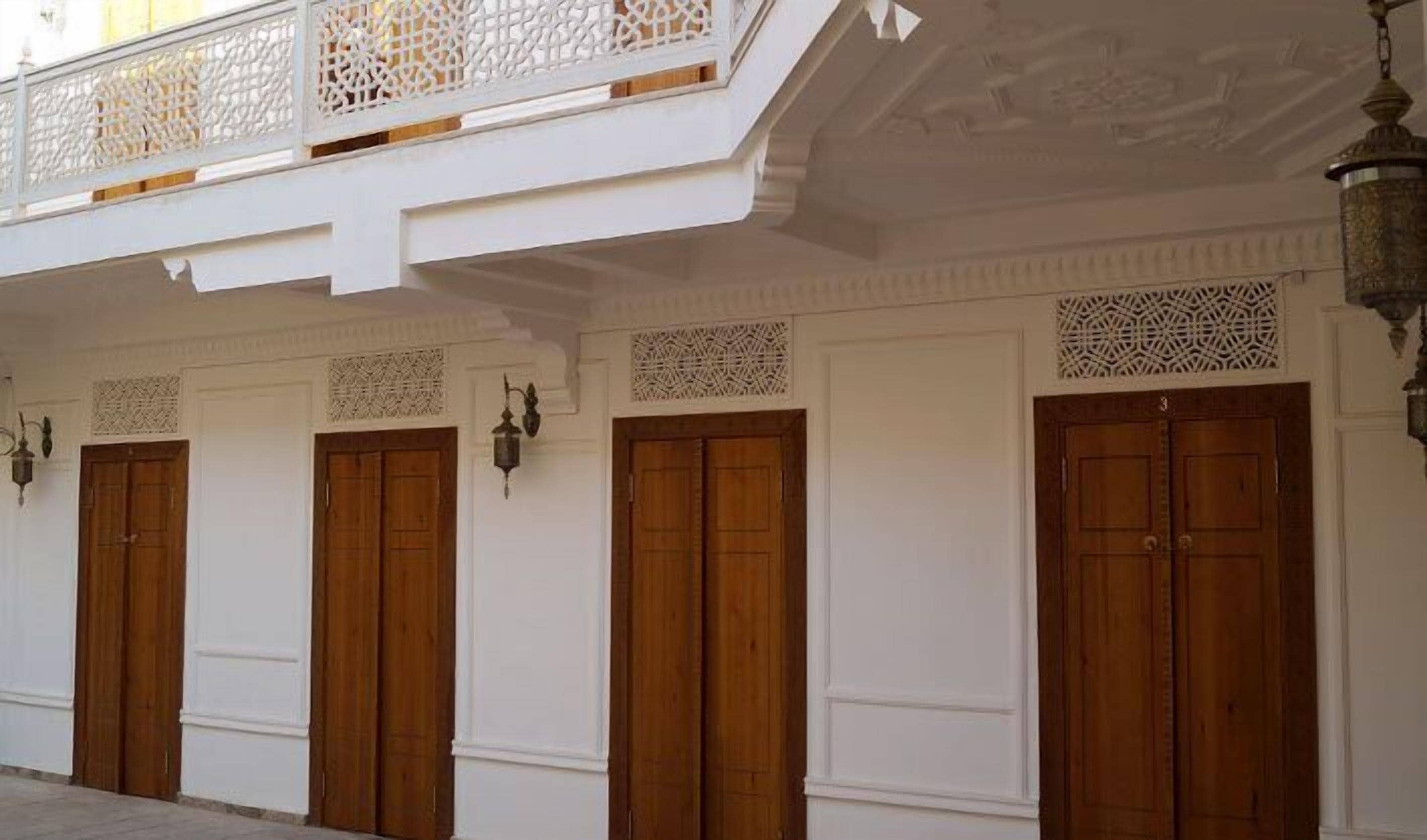 A building facade with three wooden doors, white walls, and decorative lattice patterns above the doors.