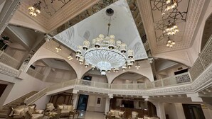 Un vestíbulo espacioso con candelabros ornamentados, una recepción y zonas de estar lujosas.