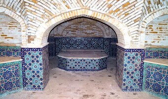 Un horno de ladrillo en arco con paredes de azulejos estampados y una chimenea central.