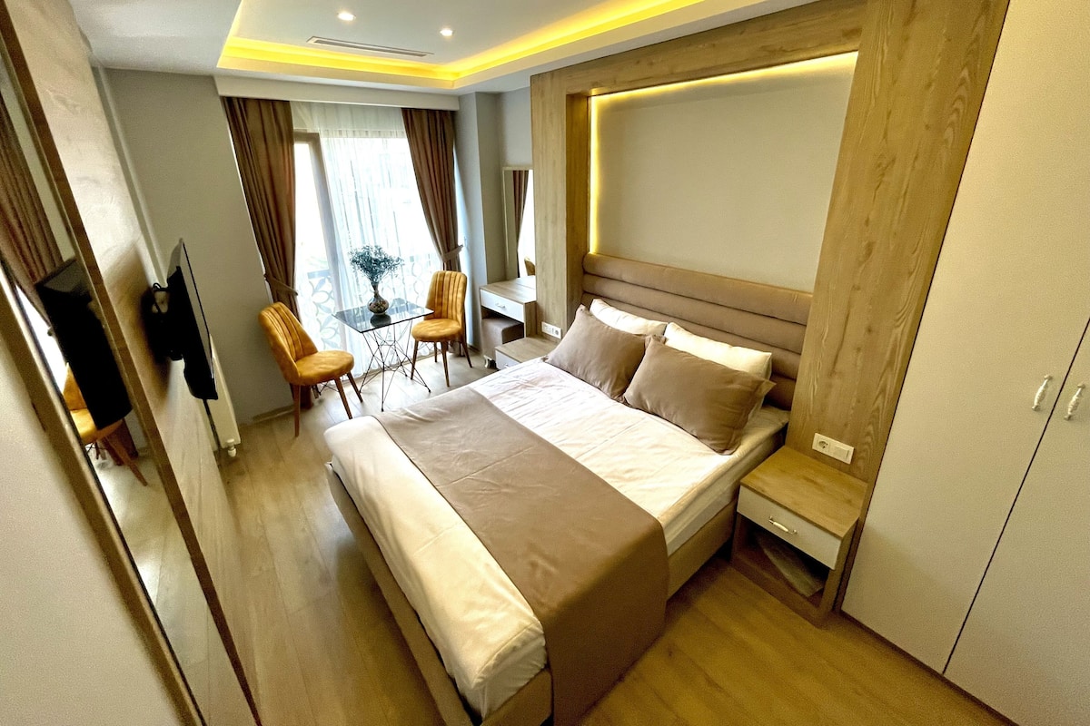 A modern hotel room with a large bed, bedside tables, a desk, and a chair.