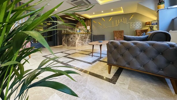 A hotel lobby with a reception desk, seating area, and a wall with a cityscape mural. - Zem Hotel (Istanbul)