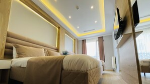 A modern bedroom with a large bed, wooden headboard, and a flat-screen TV mounted on the wall. - Zem Hotel (Istanbul)