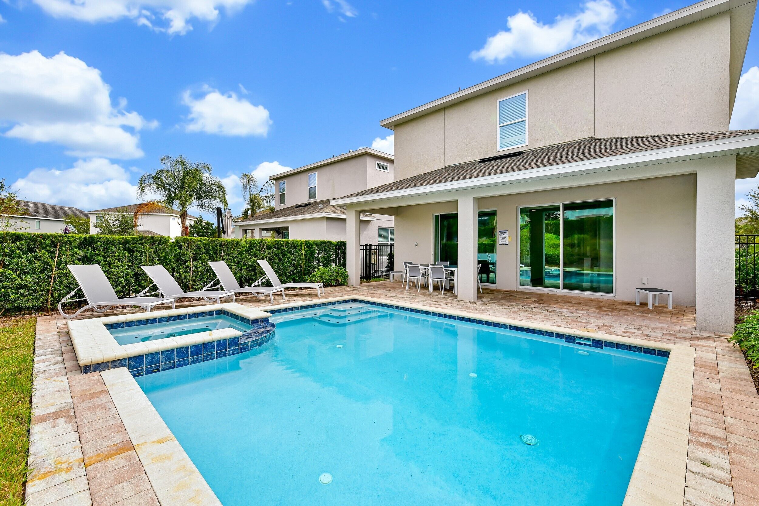 A swimming pool with lounge chairs, a patio area, and a building with large windows.