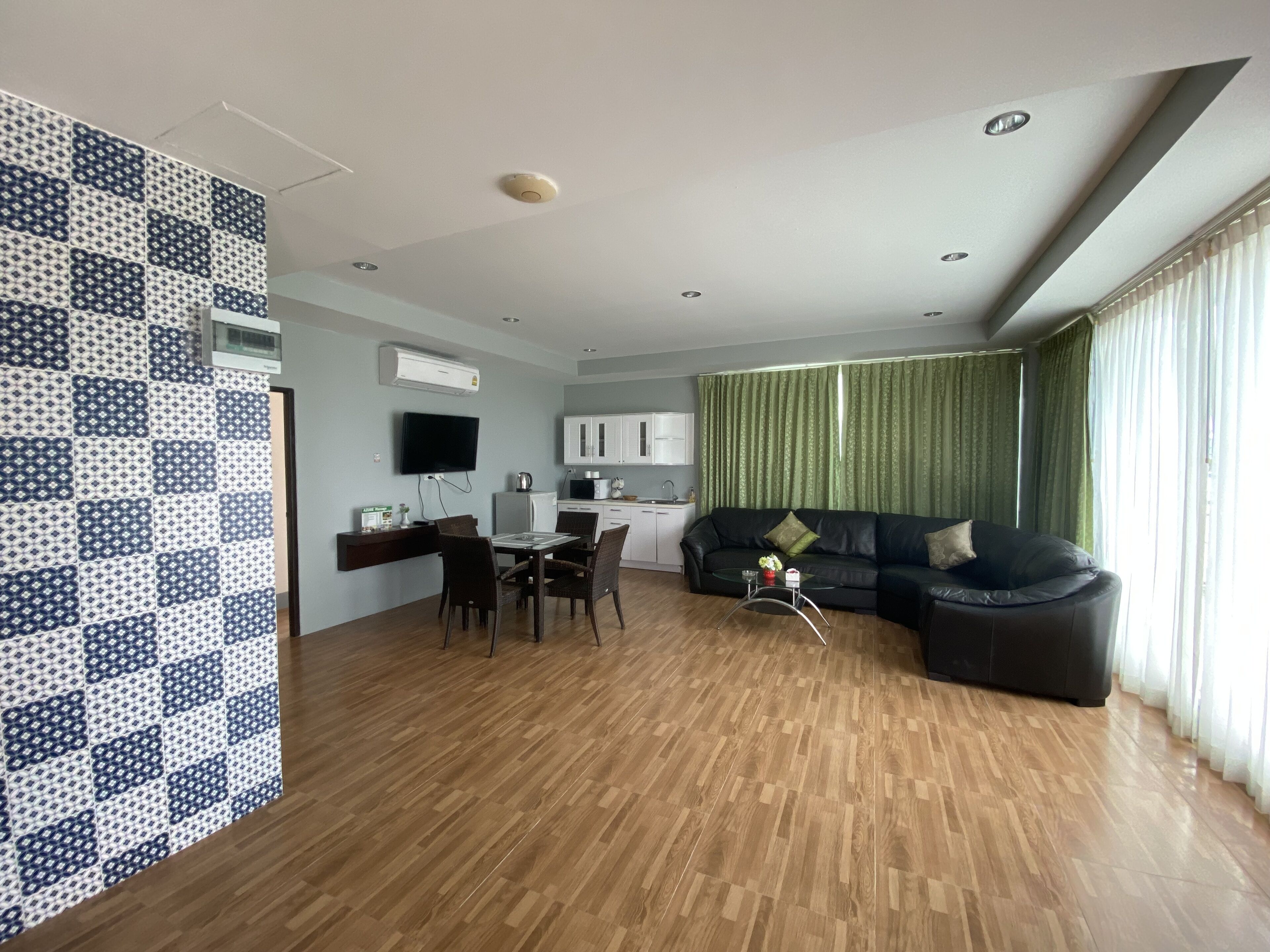 A modern living room with a dining area, a kitchen, and a large window with curtains.