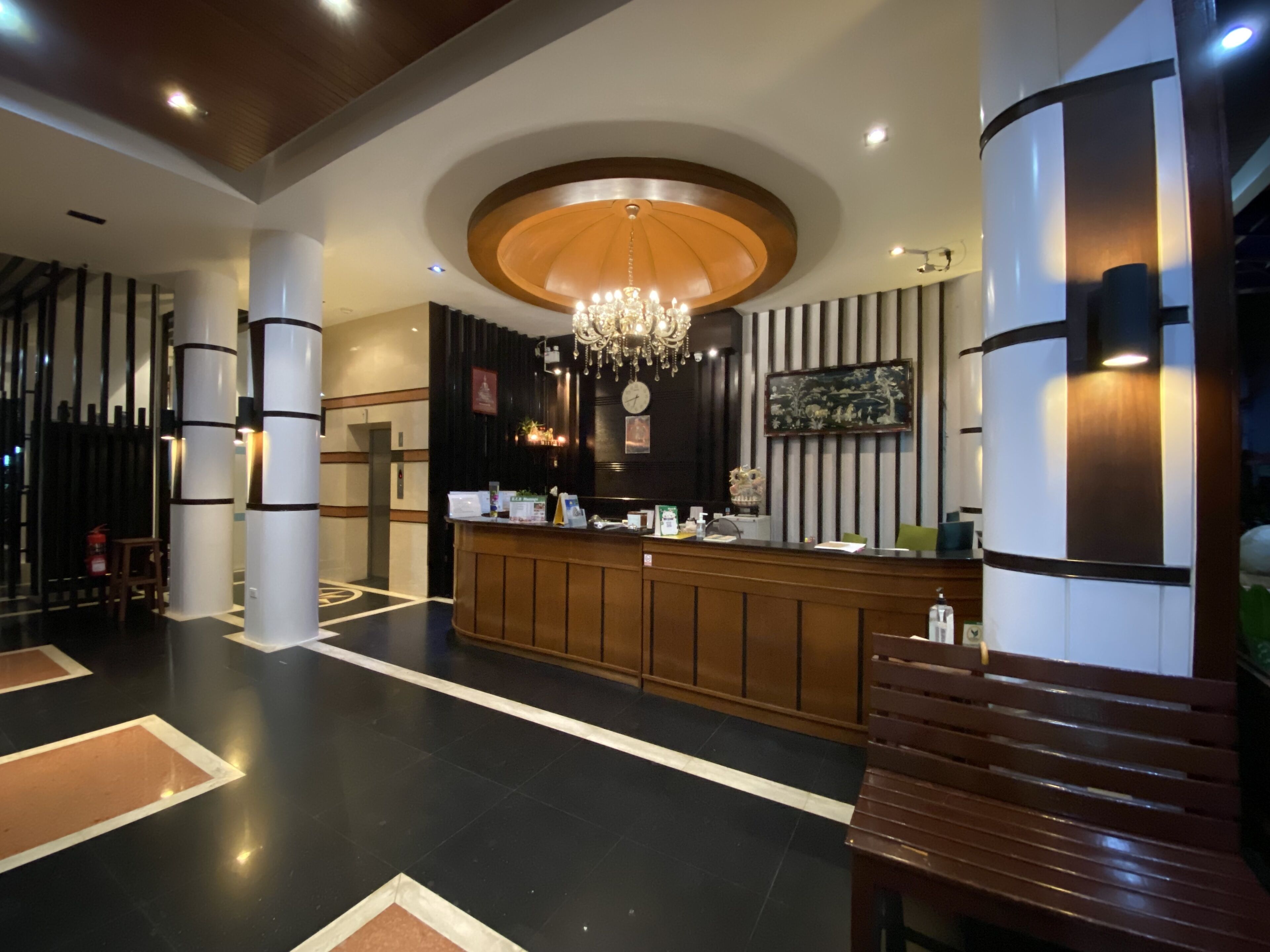 A reception area with a wooden reception desk, a chandelier, and a clock on the wall.